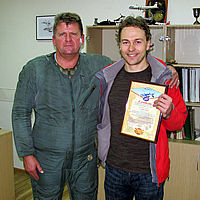 Harijs receives a framed flight certificate from pilot Andrey Pechionkin.